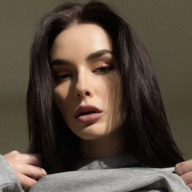 Agnieszka Brabec: Long dark hair and a gray top in a softly lit close-up.